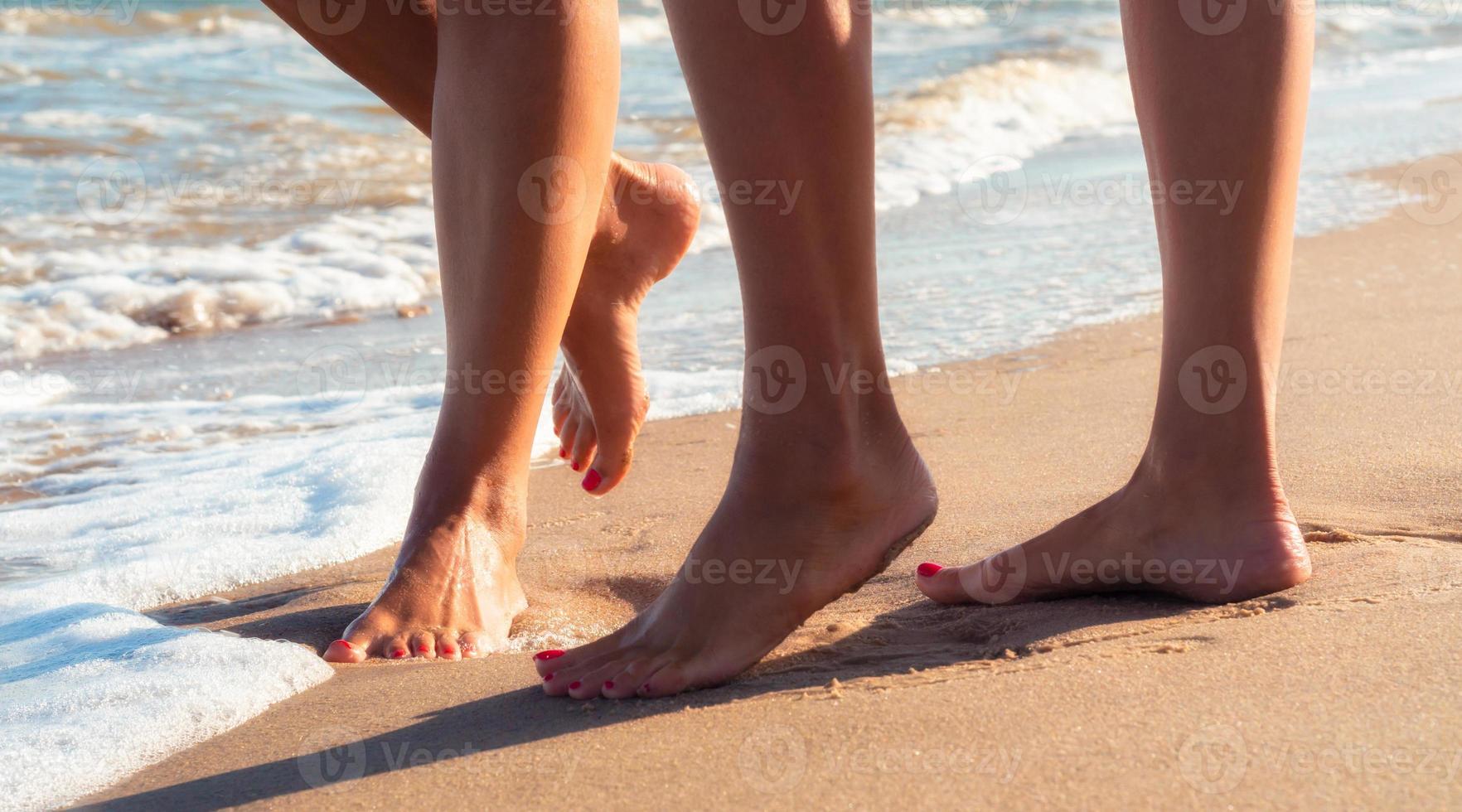 i piedi di due persone nella sabbia foto