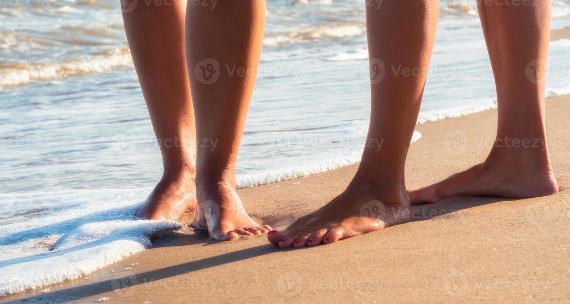 due persone che camminano sul primo piano spiaggia foto