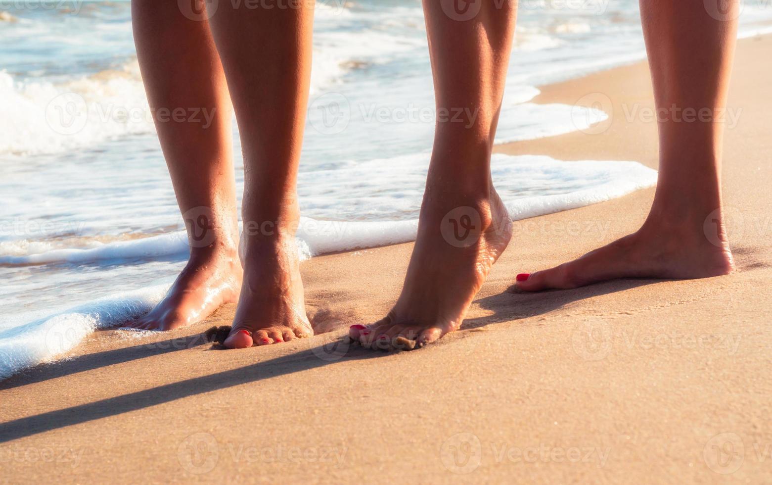 primo piano dei piedi di due persone nella sabbia foto