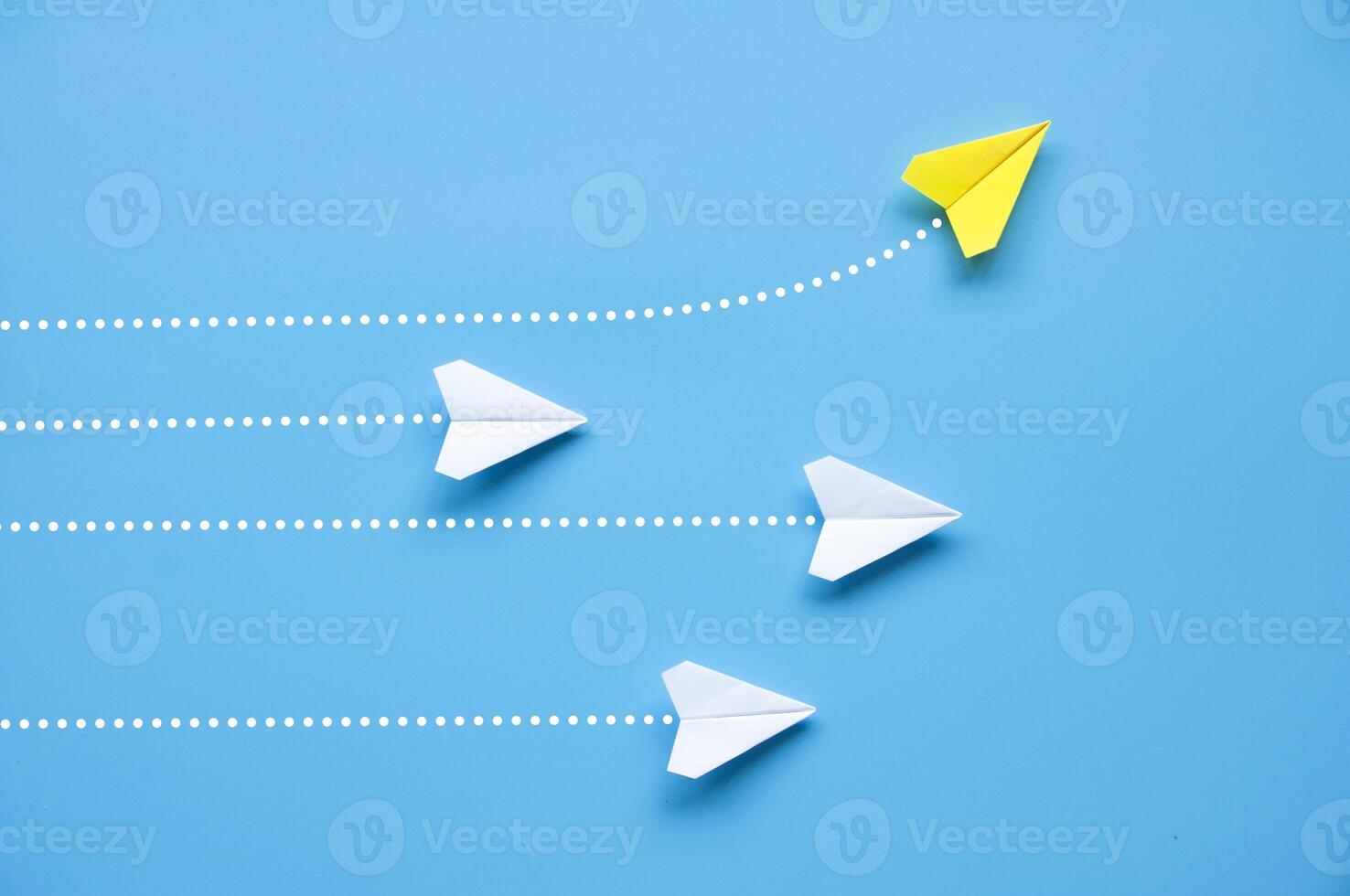 superiore Visualizza di carta aereo - giallo carta aereo origami volante per un' diverso direzione in partenza altro bianca aeroplani su blu sfondo foto