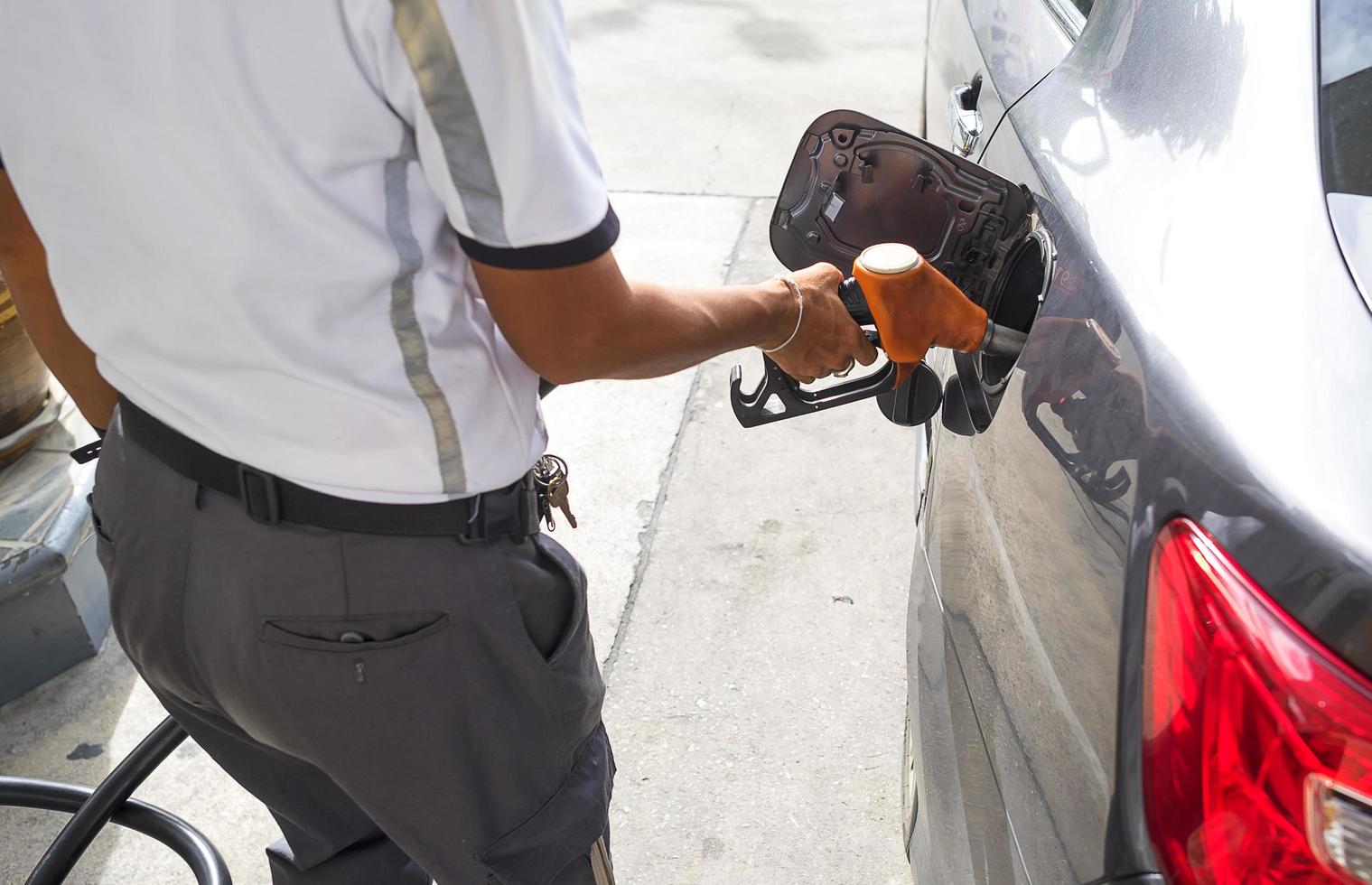 uomo che pompa carburante benzina in auto in una stazione di servizio foto