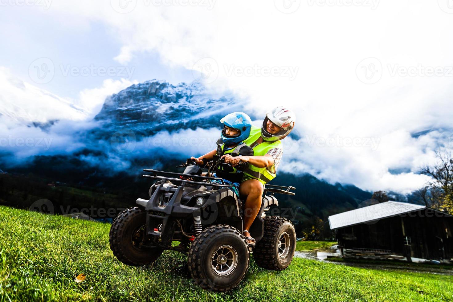 contento famiglia equitazione e guardare quadrilatero bicicletta su montagna. carino ragazzo su quadriciclo. famiglia estate vacanza attività. foto