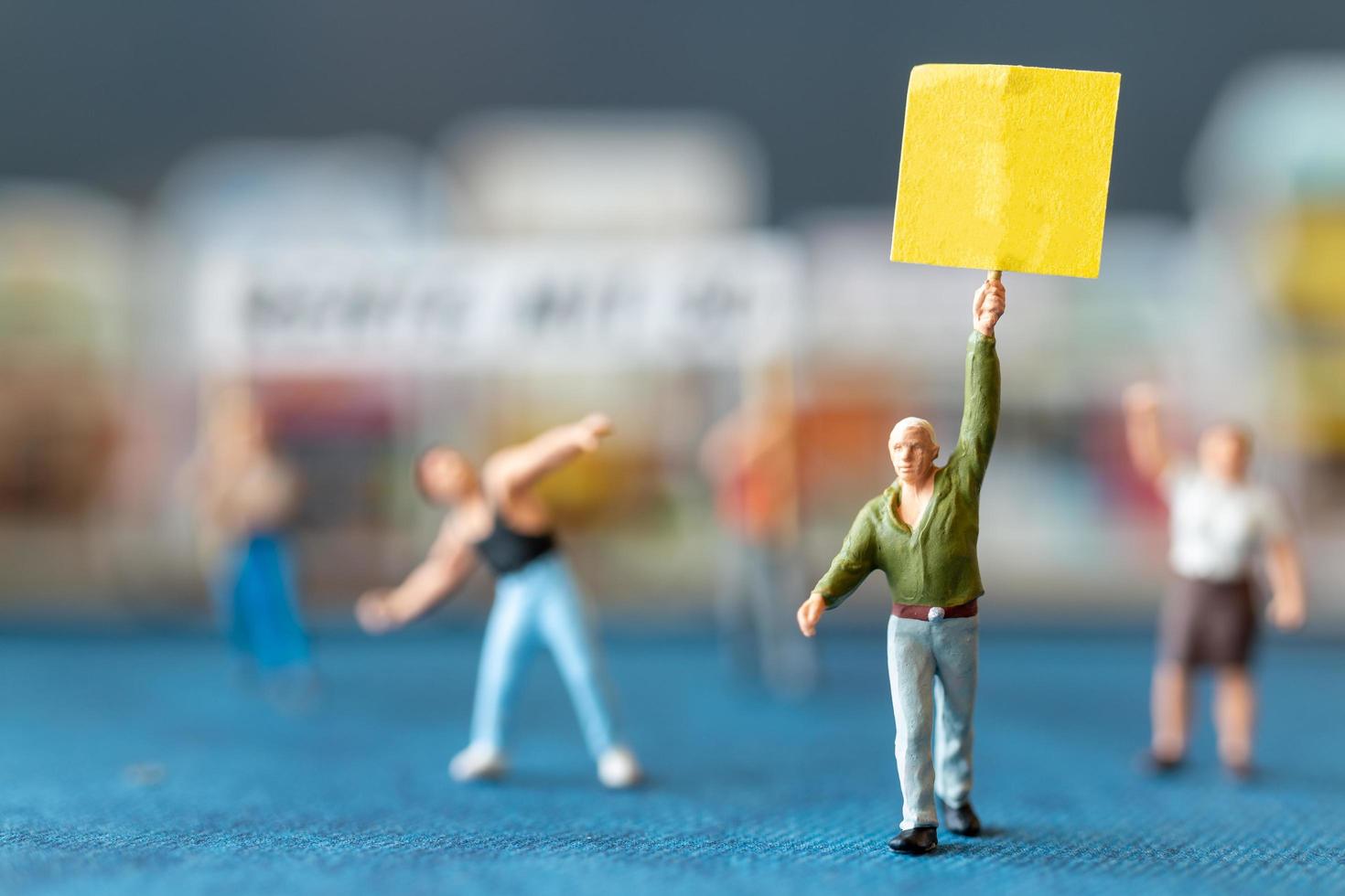 persone in miniatura, manifestanti con cartelli, alzando la mano per la rivoluzione, protestando contro il concetto foto