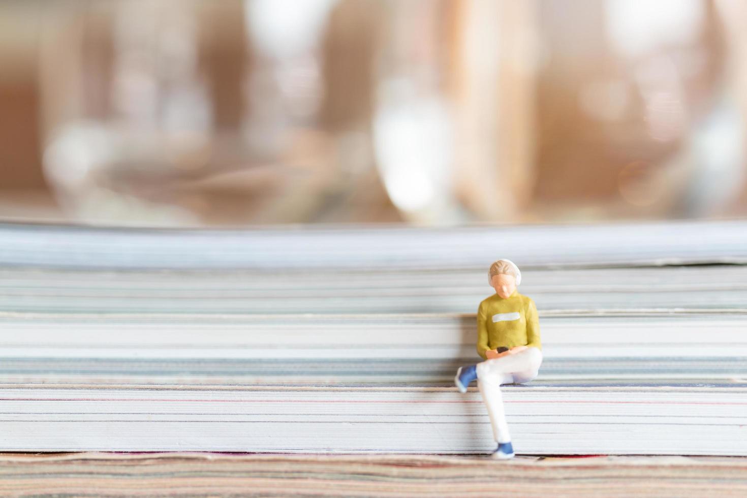 donna in miniatura che indossa le cuffie e ascolta la musica su uno smartphone foto