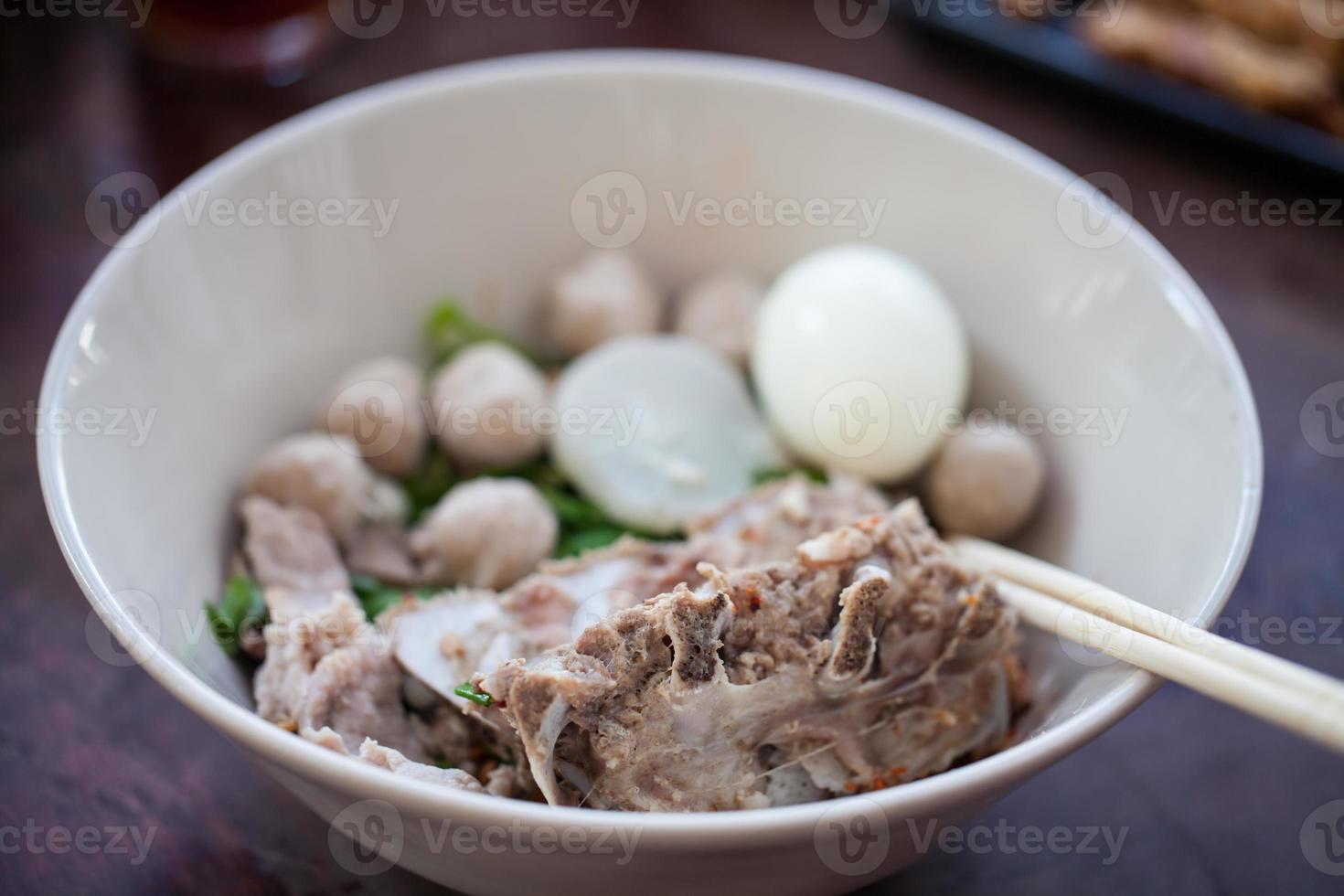 tagliatelle tailandesi con carne di maiale e polpette di carne in un piatto bianco foto