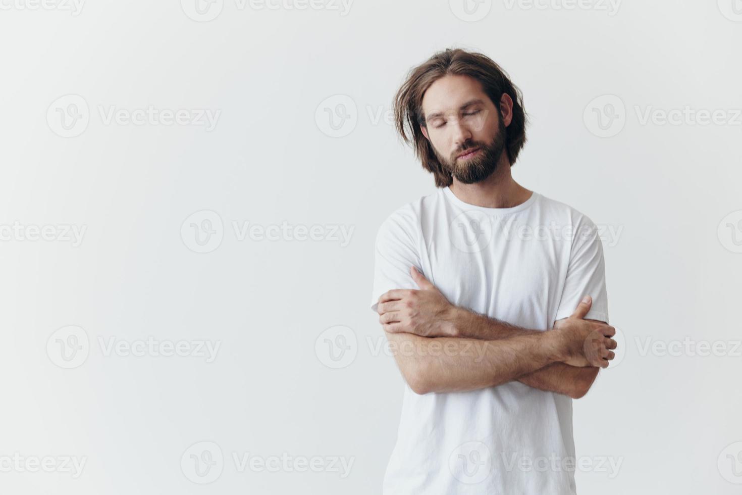 ritratto di un' triste uomo con un' nero di spessore barba e lungo capelli nel un' bianca maglietta su un' bianca isolato sfondo foto