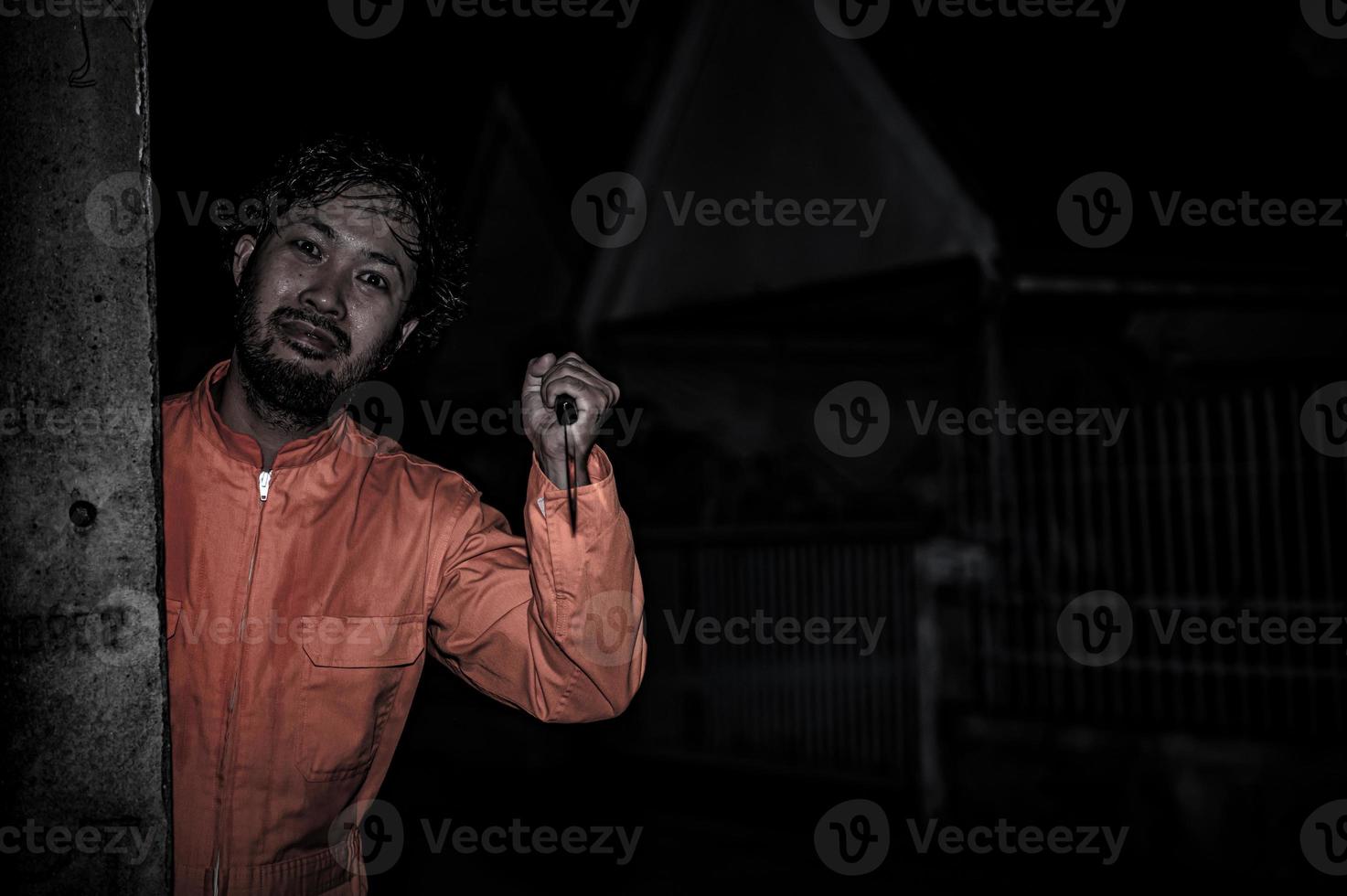 asiatico bello uomo indossare clown maschera con arma a il notte scena, halloween Festival concetto, orrore pauroso foto di un' uccisore nel arancia stoffa