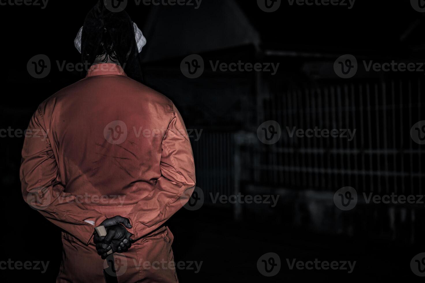 asiatico bello uomo indossare clown maschera con arma a il notte scena, halloween Festival concetto, orrore pauroso foto di un' uccisore nel arancia stoffa