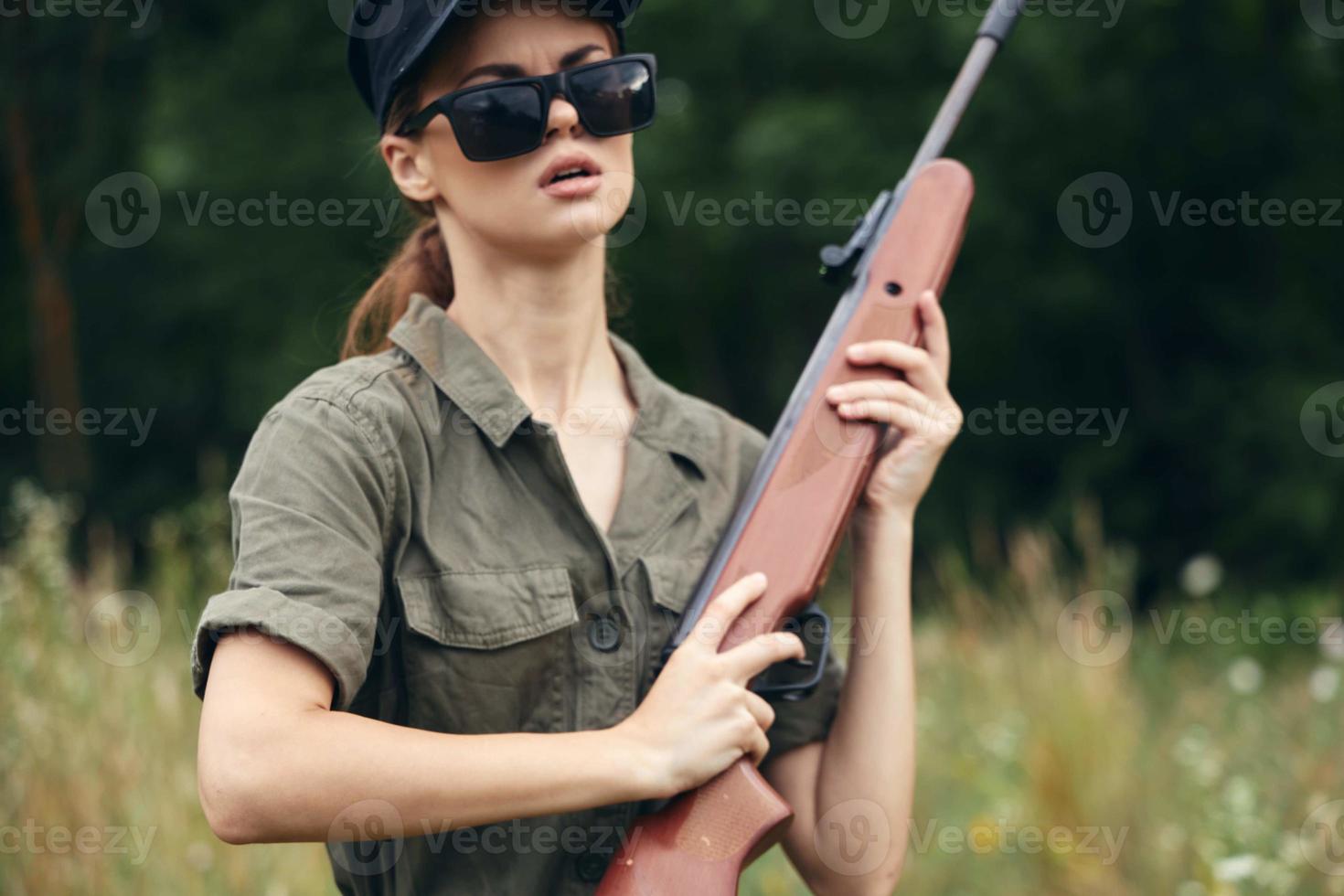 donna su all'aperto a caccia con un' arma nel il suo mani verde le foglie foto