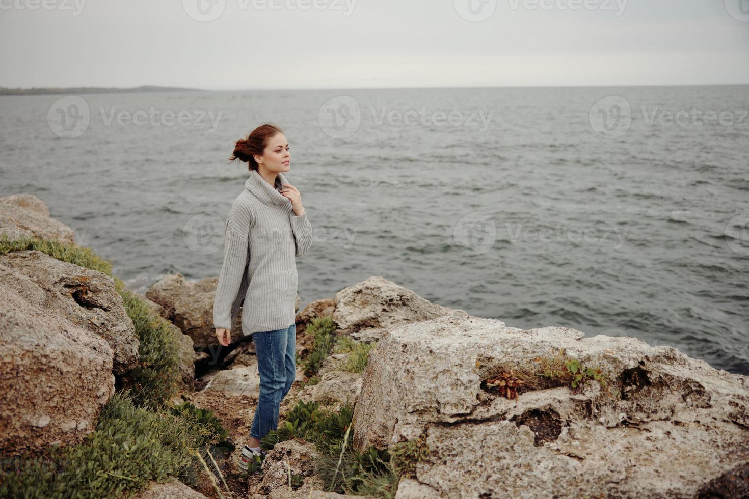 donna nel un' grigio maglione sta su un' roccioso riva natura inalterato foto