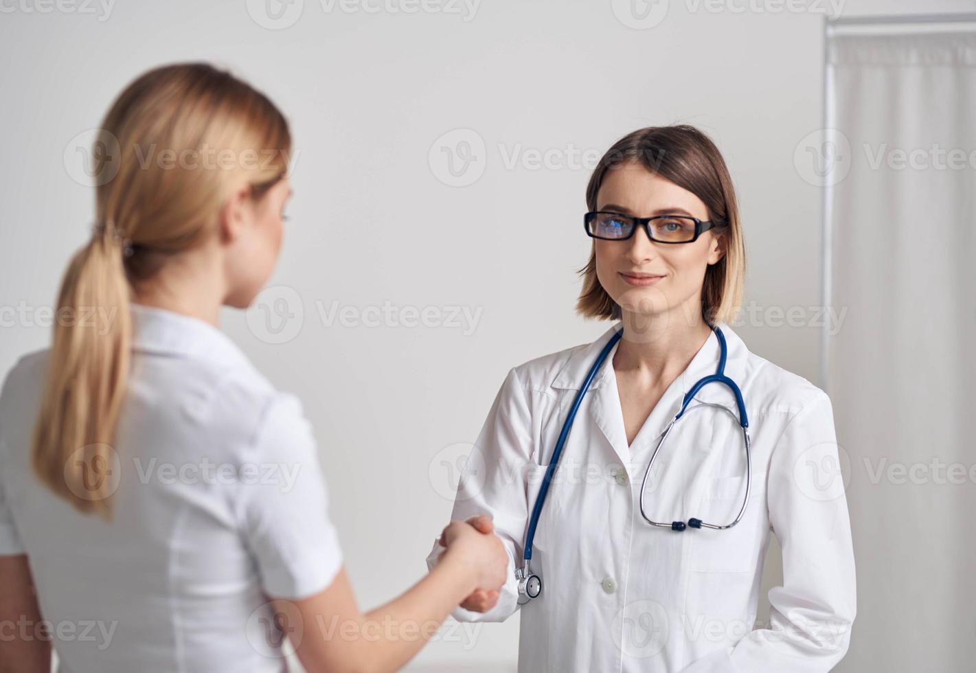 medico e paziente tremante mani su un' leggero sfondo stetoscopio in giro il collo foto
