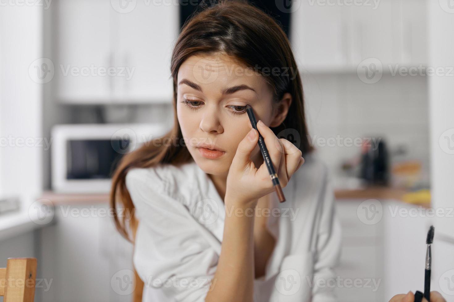 donna con eyeliner nel mano con trucco nel un' luminosa camera foto