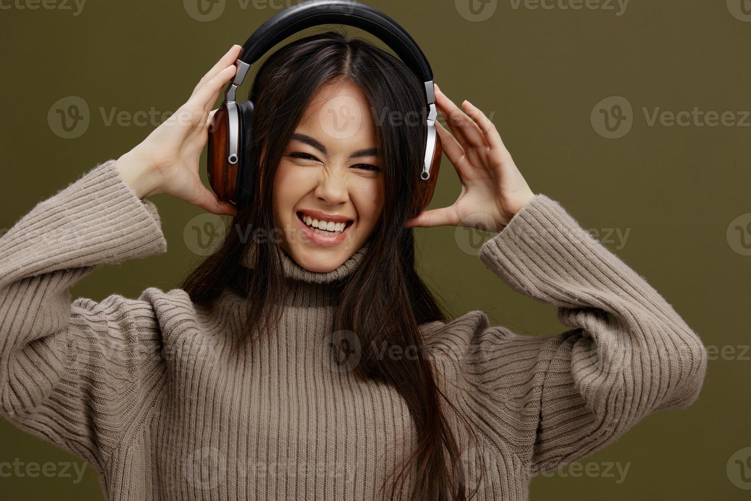 ritratto donna nel un' maglione ascoltando per musica con cuffie divertimento verde sfondo foto