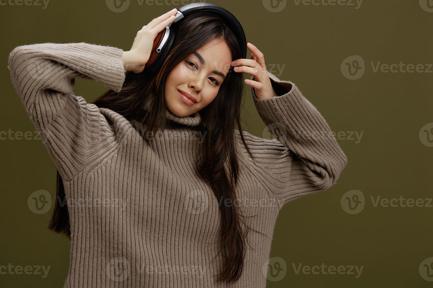giovane donna nel un' maglione ascoltando per musica con cuffie divertimento verde sfondo foto