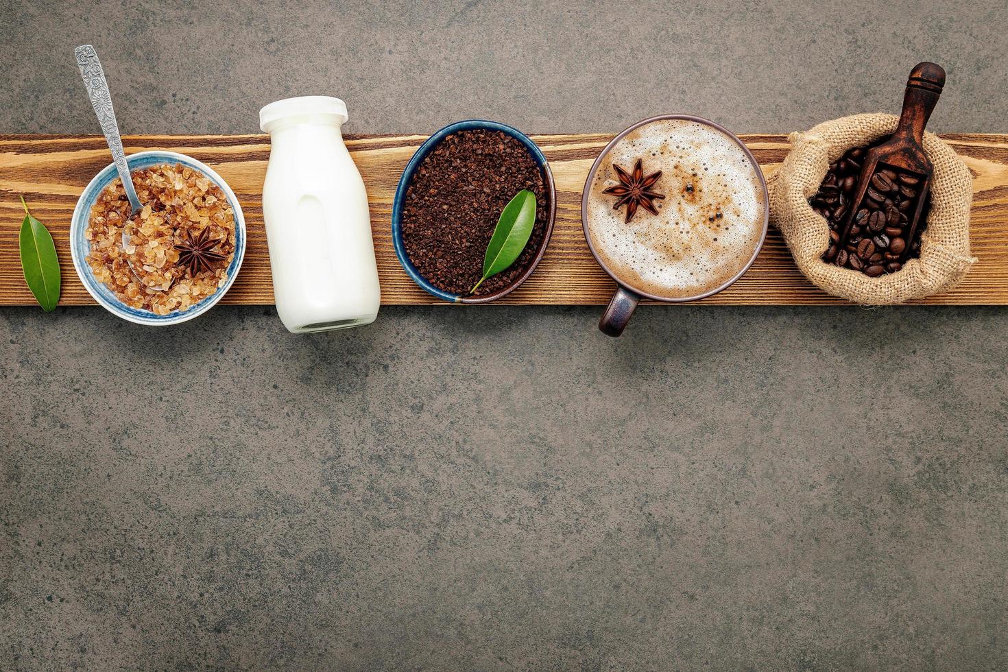 chicchi di caffè tostati con polvere di caffè e ingredienti saporiti per fare il caffè su uno sfondo di pietra scura foto