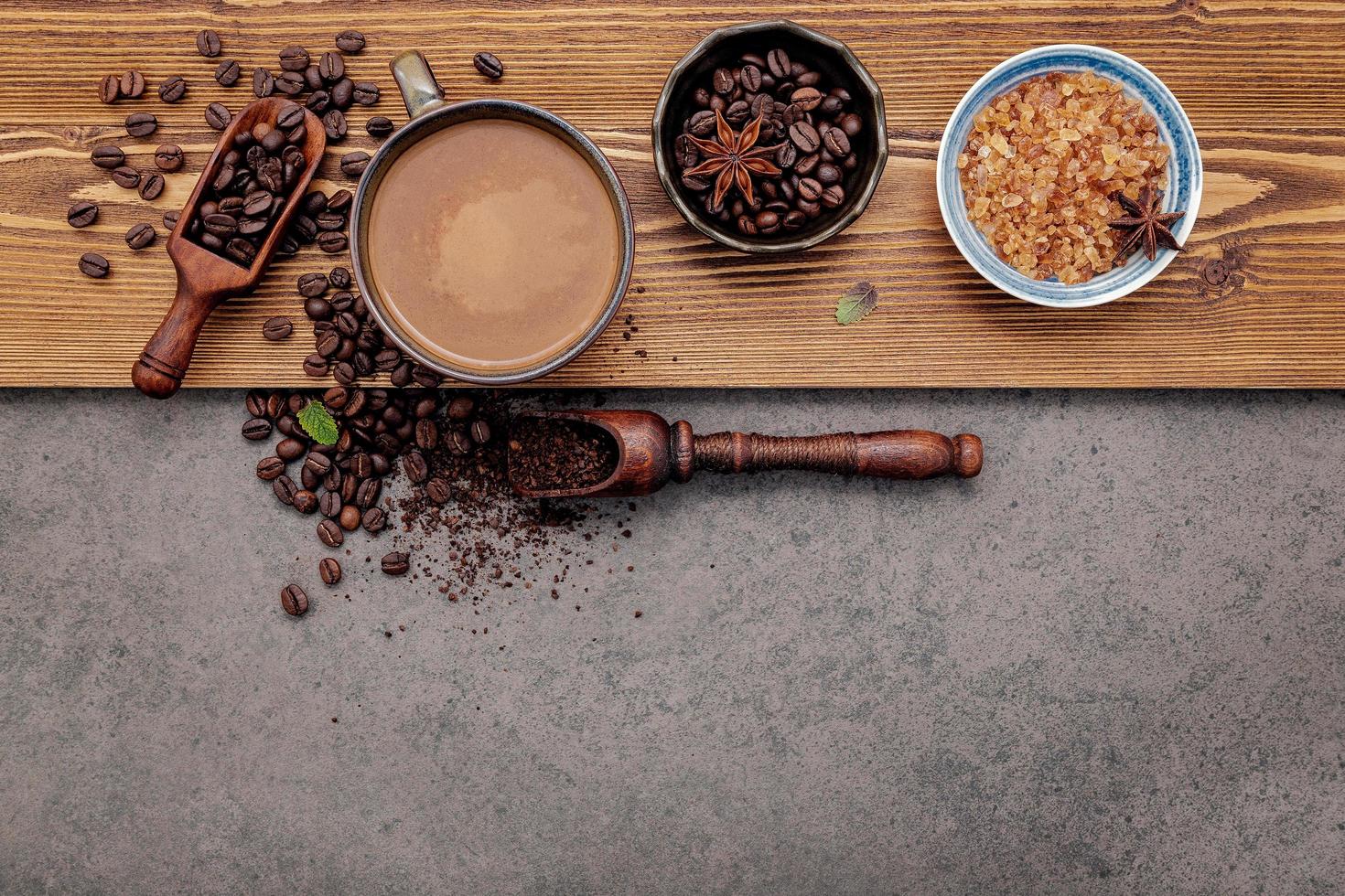 chicchi di caffè tostati con una tazza di caffè su uno sfondo di pietra scura foto