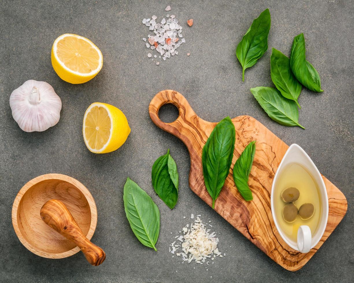 ingredienti per il pesto fatto in casa di basilico, parmigiano, aglio, olio d'oliva, limone e sale dell'Himalaya su uno sfondo di cemento scuro foto