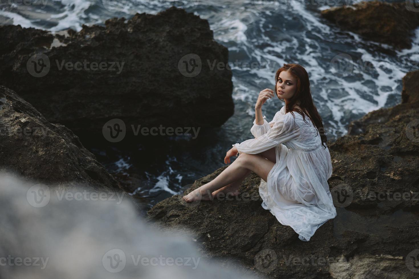 donna nel bianca vestito roccioso azienda natura oceano onde inalterato foto