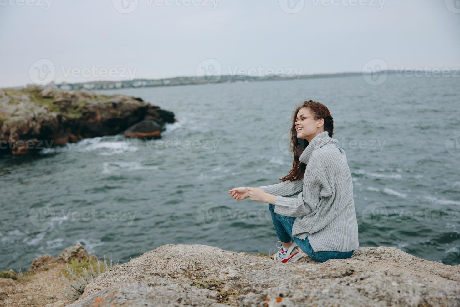 ritratto di un' donna seduto su il costa maglione paesaggio inalterato foto