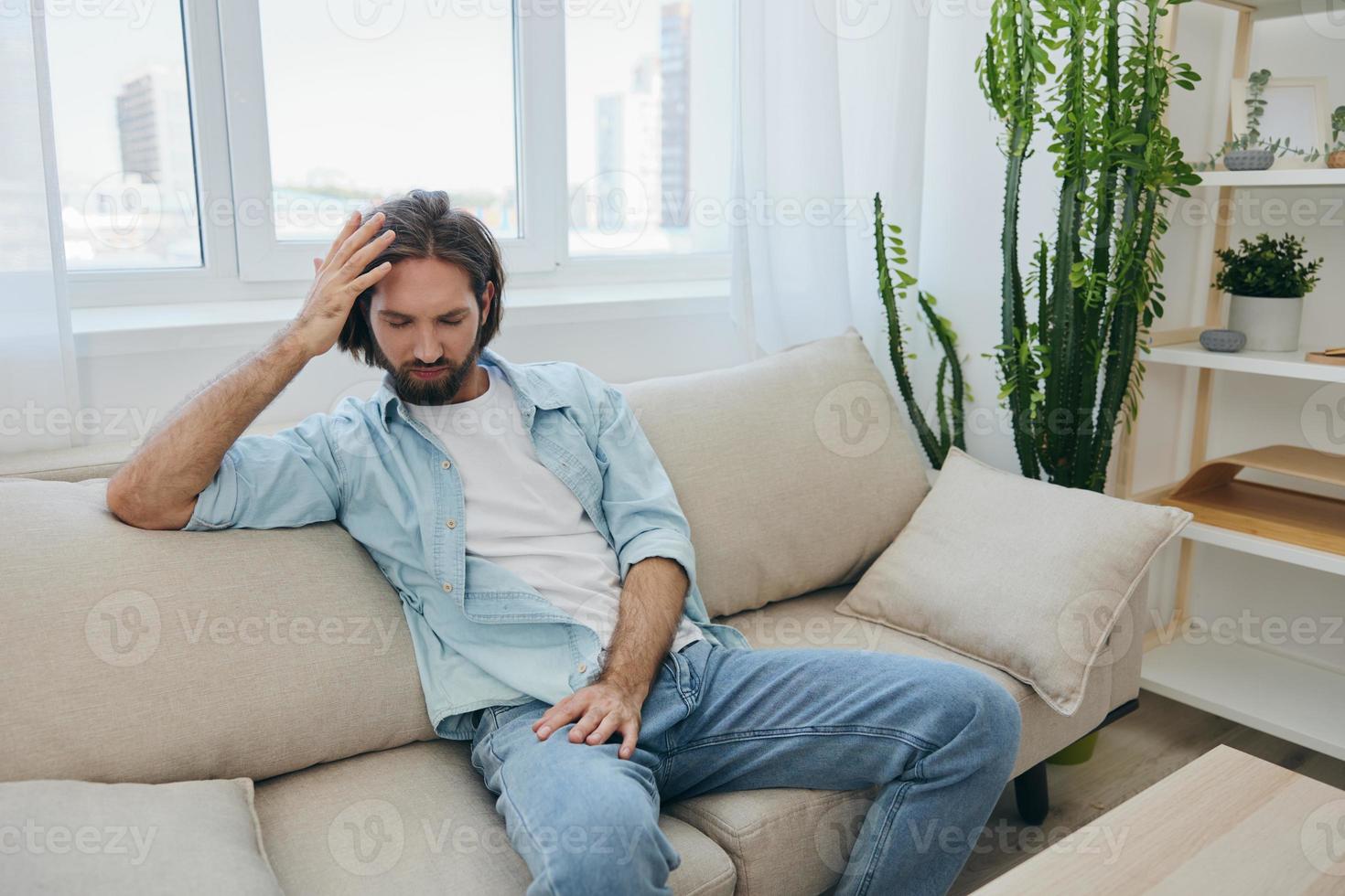 un' giovane maschio libero professionista si siede su il divano dopo un' esigente lavoro e riposa purtroppo pendente su il divano. foto