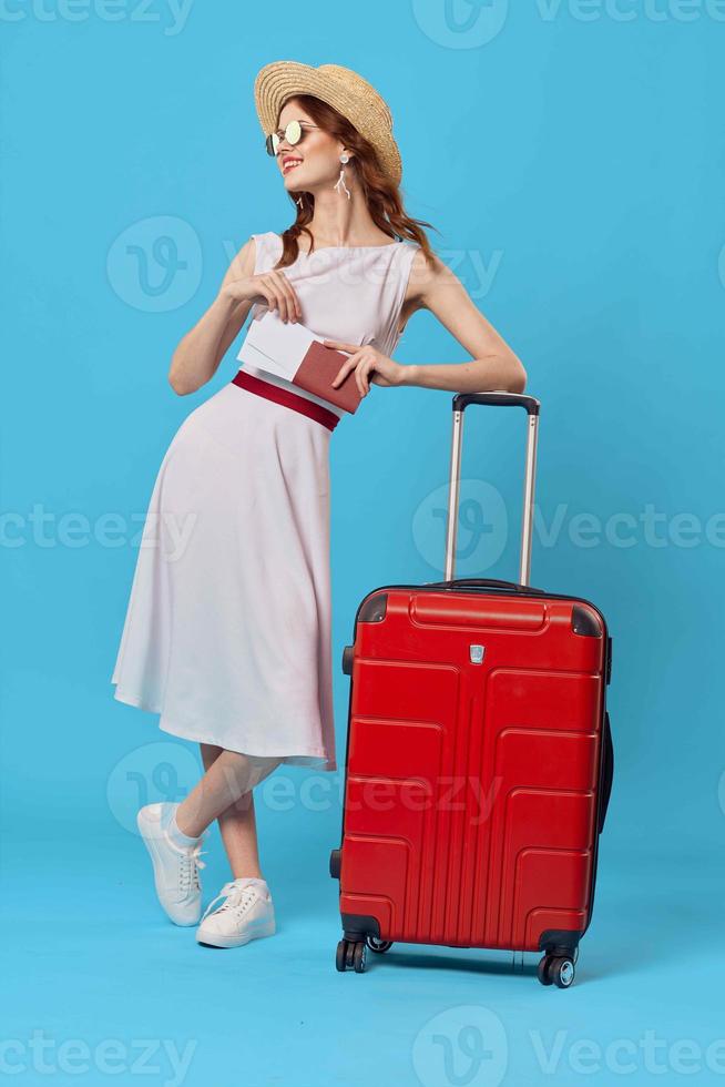 donna nel bianca vestito rosso valigia viaggio destinazione blu sfondo foto