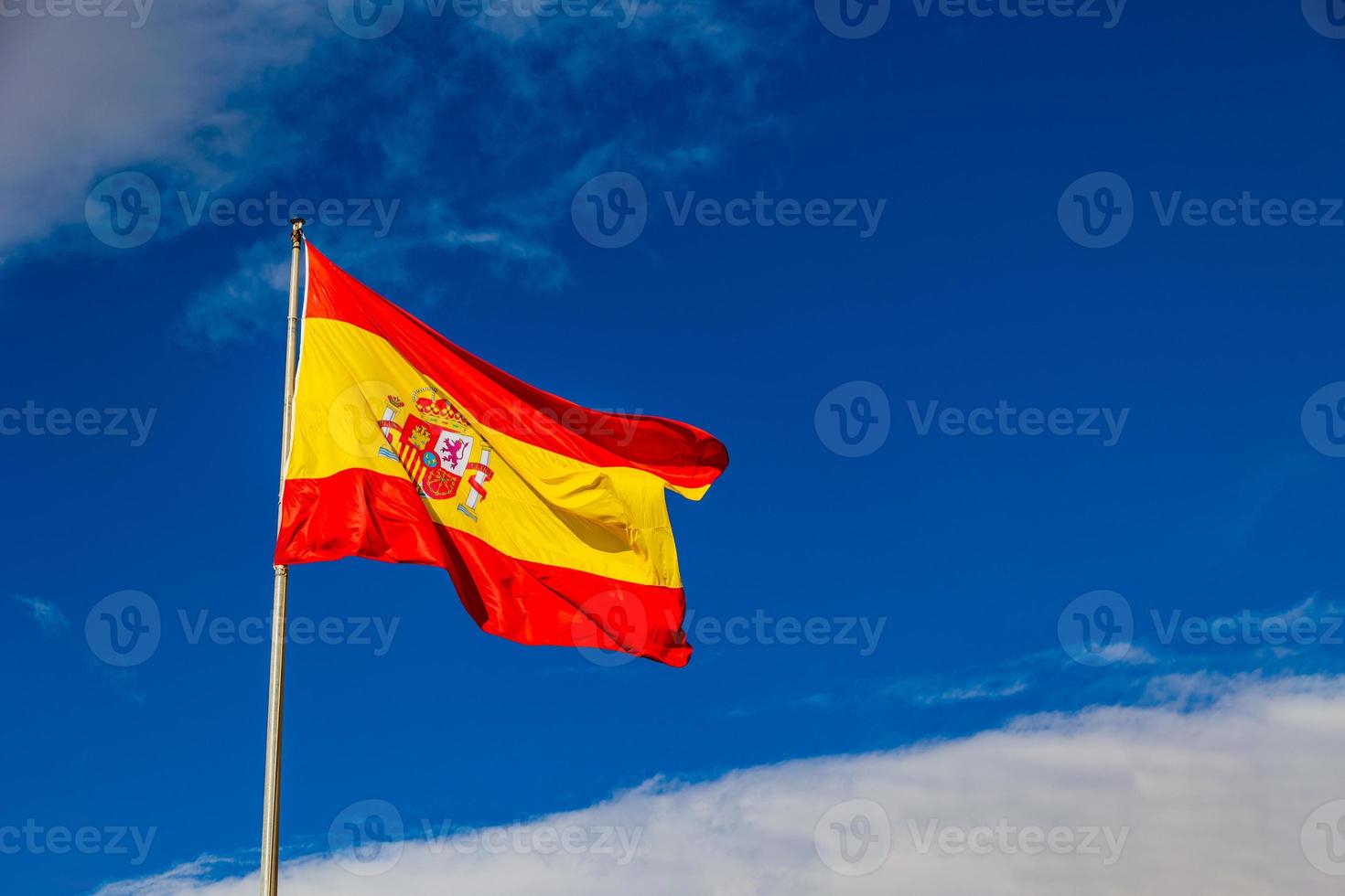 bandiera di Spagna rosso giallo su blu cielo sfondo con bianca nuvole foto