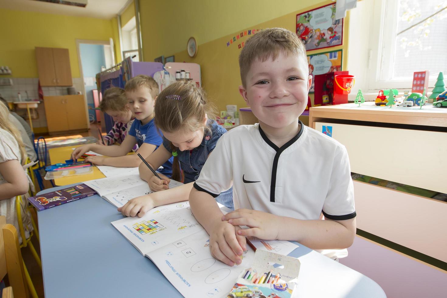 bambini nel un' disegno lezione nel asilo. bambino in età prescolare con matita e taccuino foto