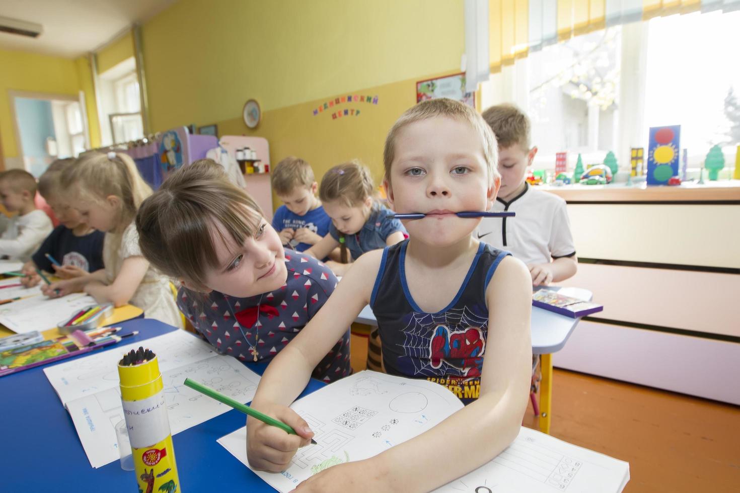 .figli nel un' disegno lezione nel asilo. divertente bambino in età prescolare con matita e taccuino foto