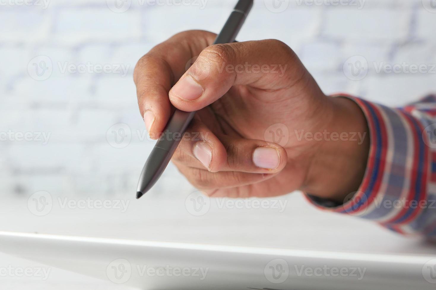 mano con la scrittura dello stilo sulla tavoletta digitale foto