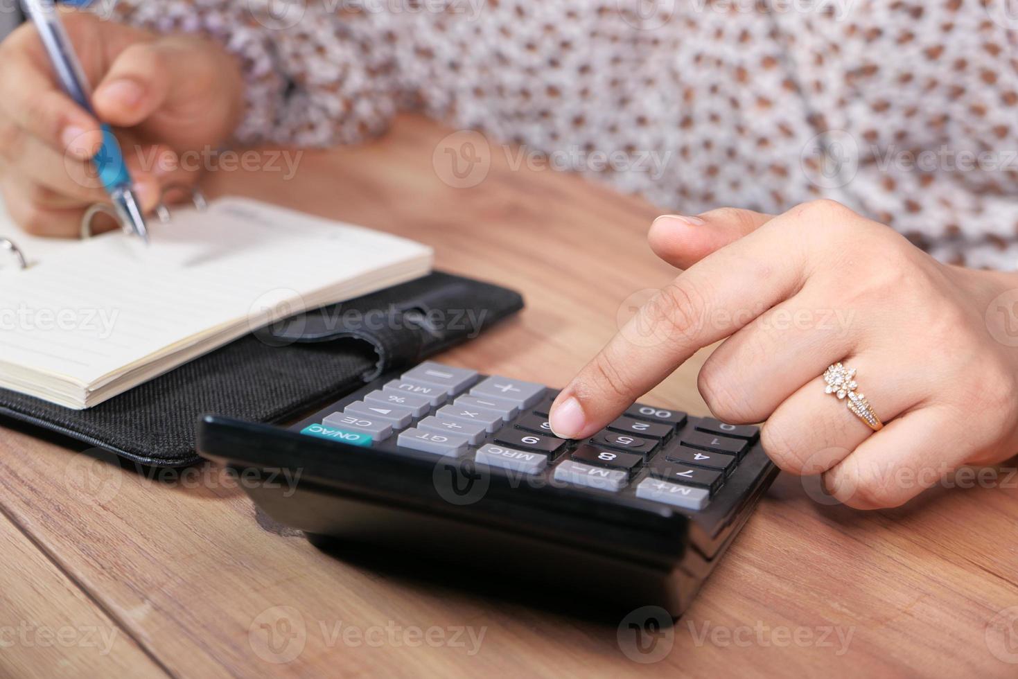 mano della donna utilizzando la calcolatrice sulla scrivania in ufficio foto