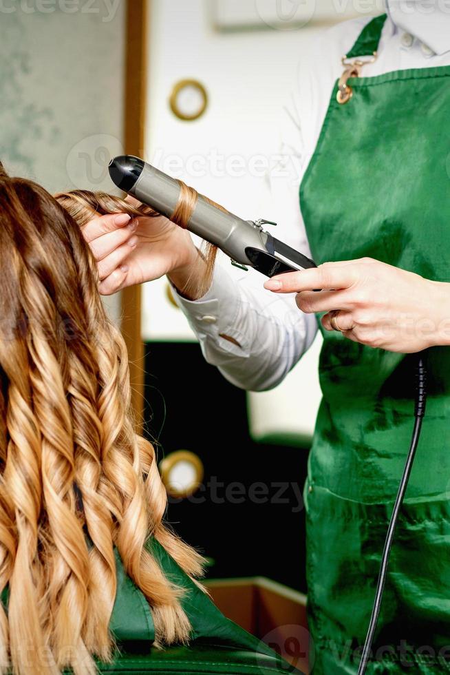 parrucchiere arricciatura capelli con arricciatura ferro foto