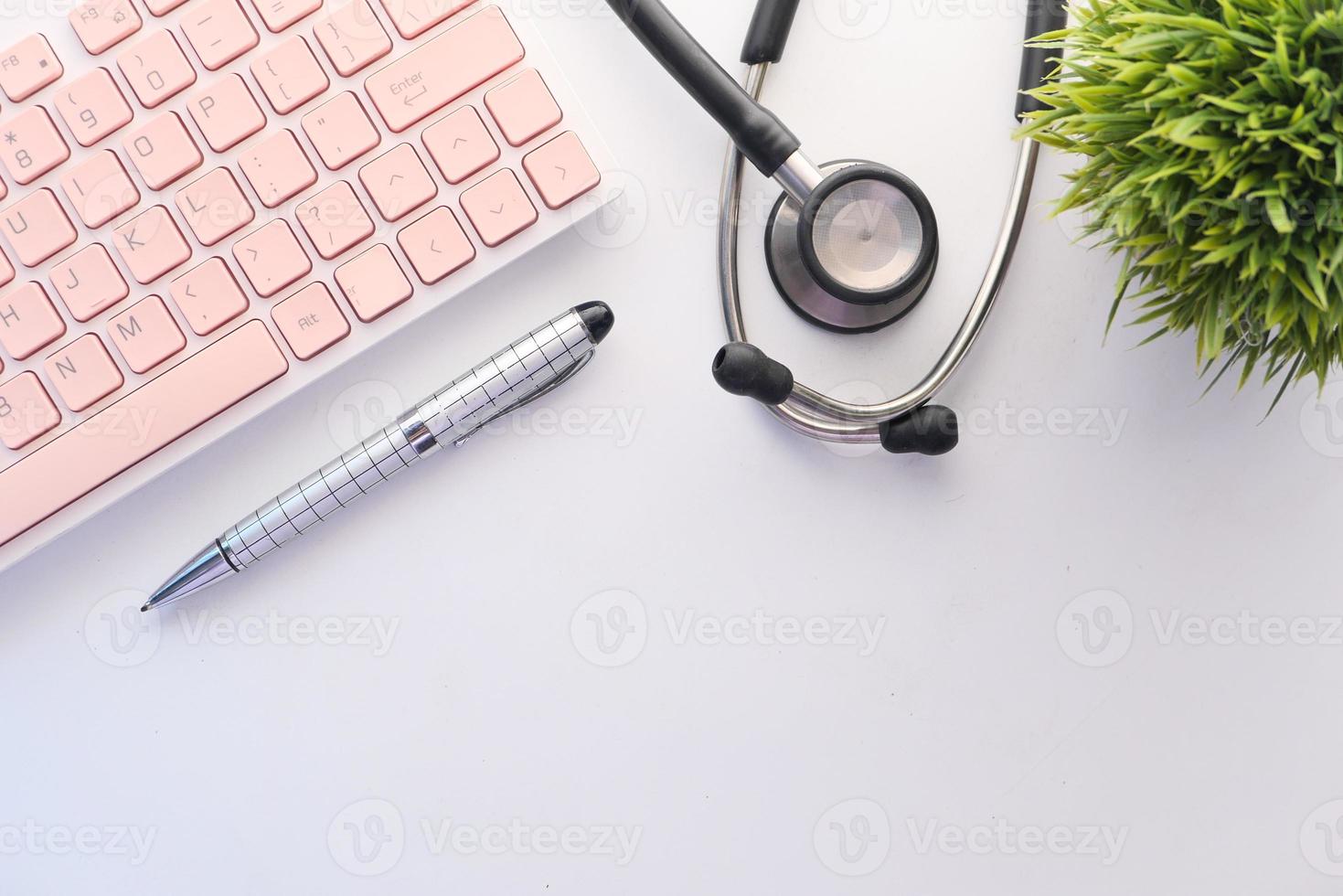 penna, tastiera e stetoscopio sulla scrivania bianca foto