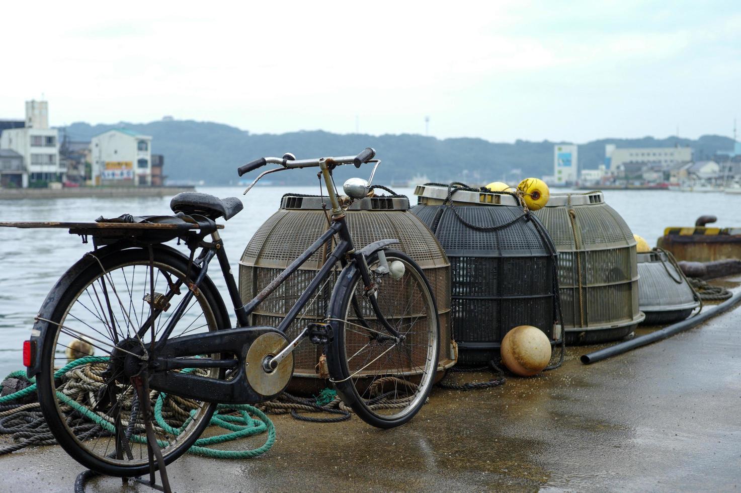 primo piano di una bicicletta d'epoca vicino ai tradizionali strumenti di pesca al porto di mare foto