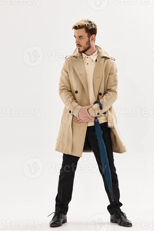 uomo nel beige cappotto ombrello nel mani Accessori moda foto