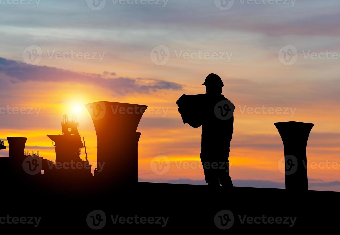 silhouette di ingegnere uomo controllo progetto a edificio luogo sfondo, infrastruttura costruzione luogo a tramonto nel sera tempo foto