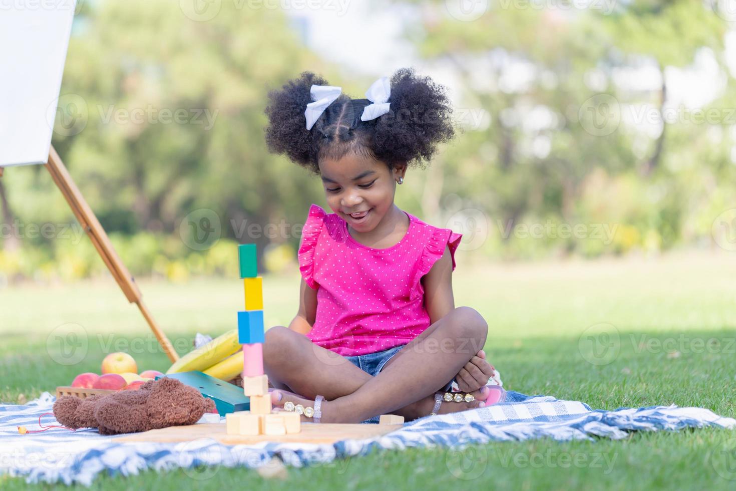 carino poco ragazza giocare giocattolo a il giardino, bambino ragazza giocando con poco di legno giocattolo all'aperto foto