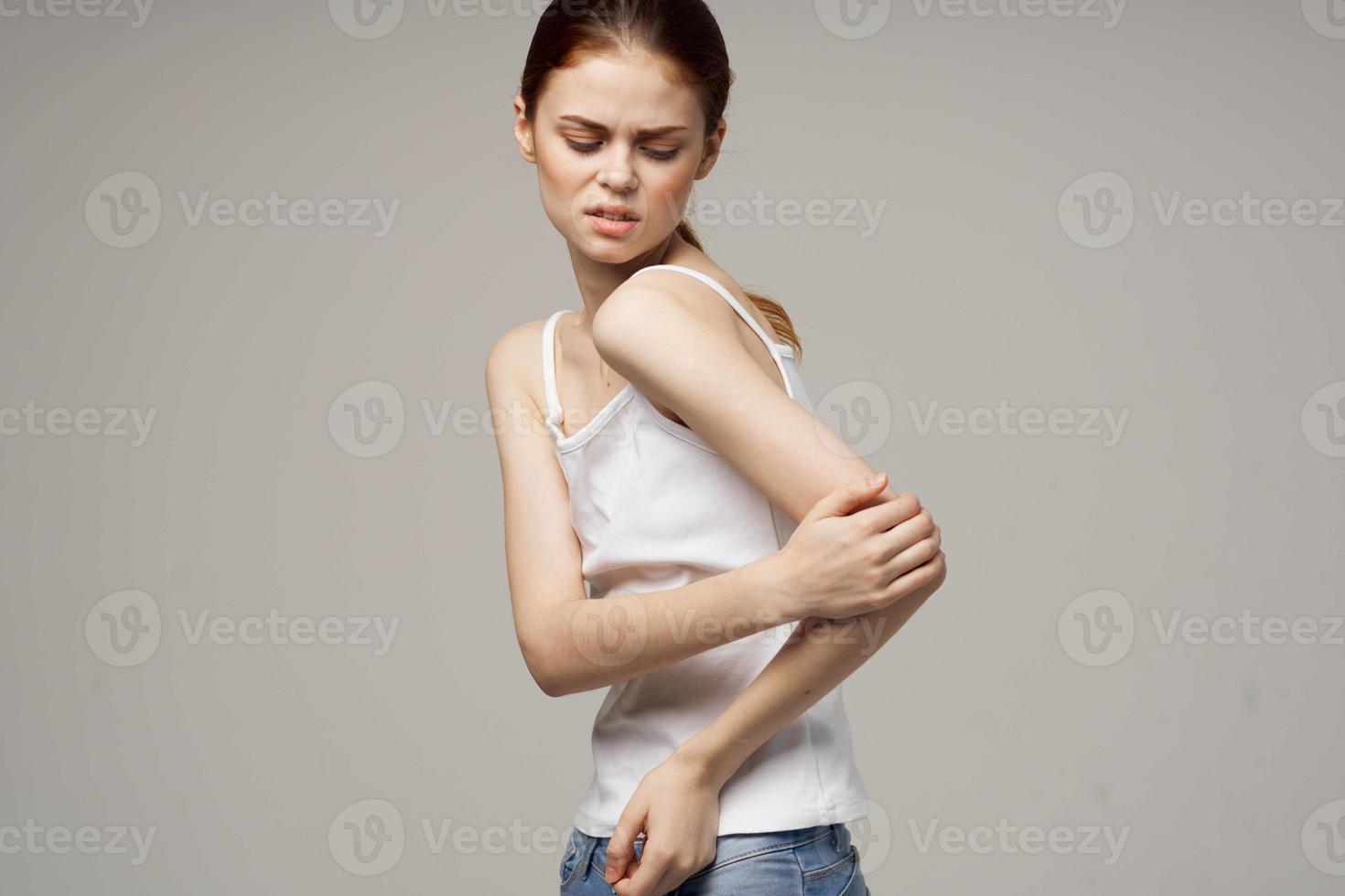 donna nel bianca maglietta Tenere su per il gomito Salute i problemi comune trattamento studio trattamento foto