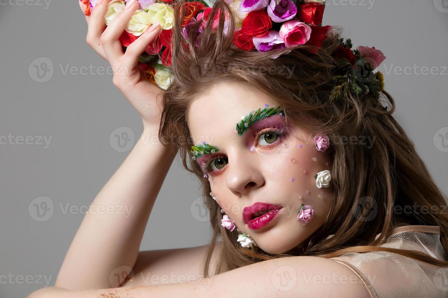 ritratto di un' bellissimo ragazza con luminosa primavera trucco. estate ragazza nel fiori. il viso di un' bellissima bellezza con esteso sopracciglia e ciglia. naturale cosmetici concetto. foto