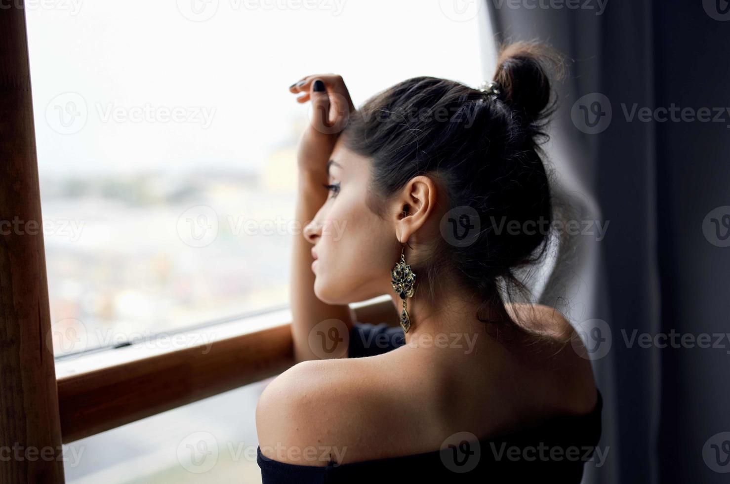 brunetta vicino finestra in posa attraente Guarda orecchini stile di vita studio foto