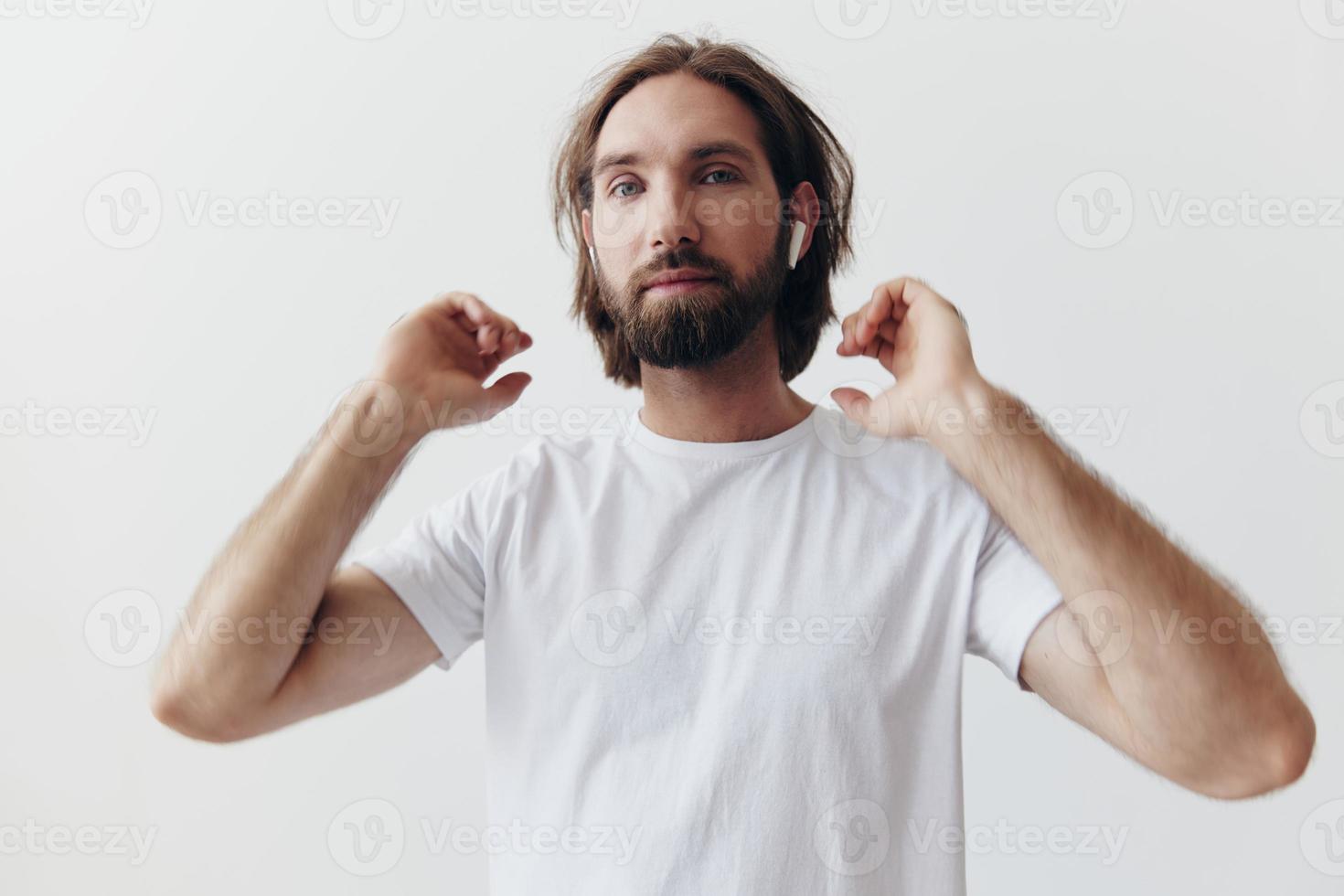 elegante uomo nel un' bianca maglietta con senza fili cuffie nel il suo orecchie avendo divertimento ascoltando per musica Sorridi su un' bianca sfondo stile di vita foto