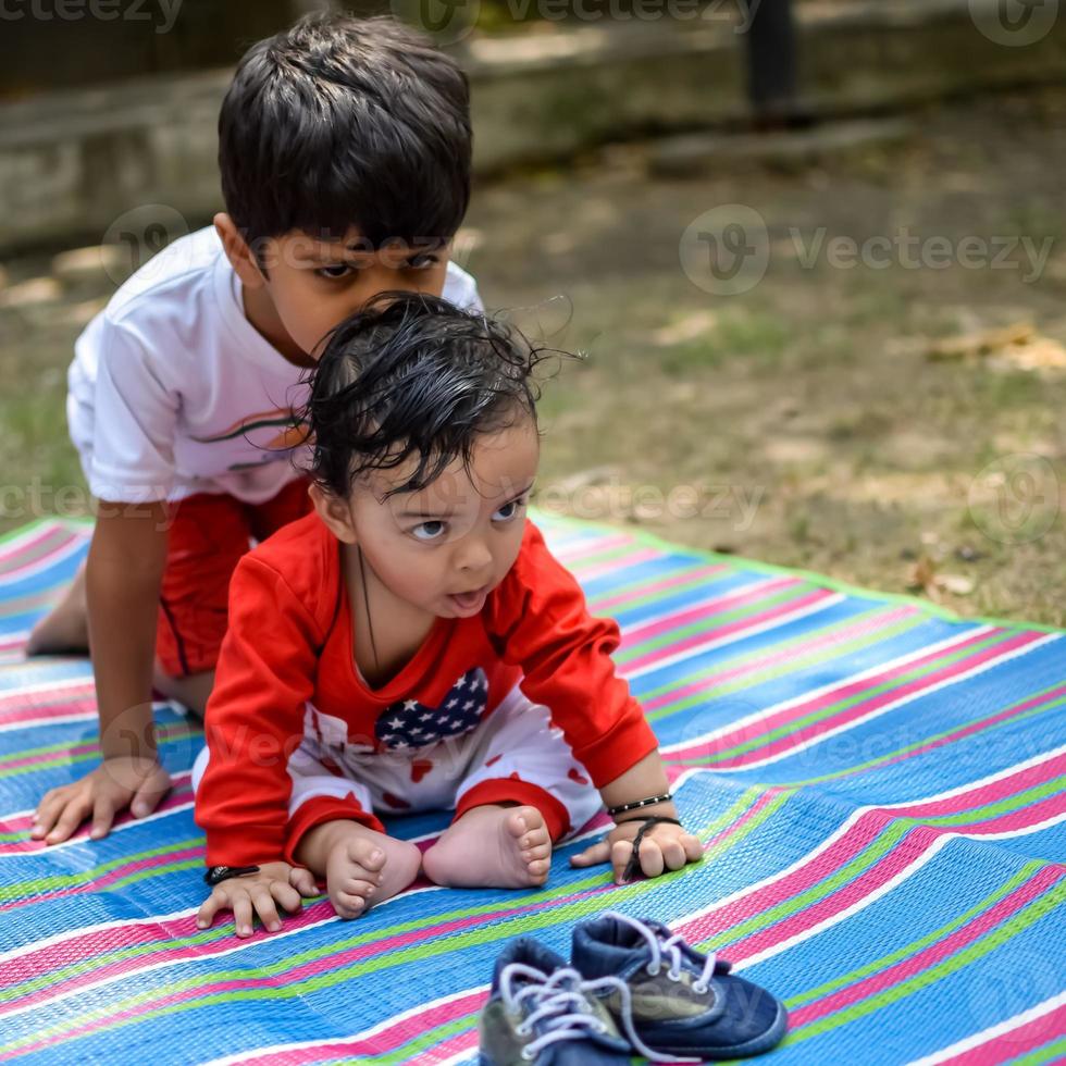 Due contento ragazzi nel società parco, contento asiatico fratelli chi siamo sorridente felicemente insieme. fratelli giocare all'aperto nel estate, migliore gli amici. bambino piccolo bambino ragazzo giocando con il suo contento fratello nel il giardino foto