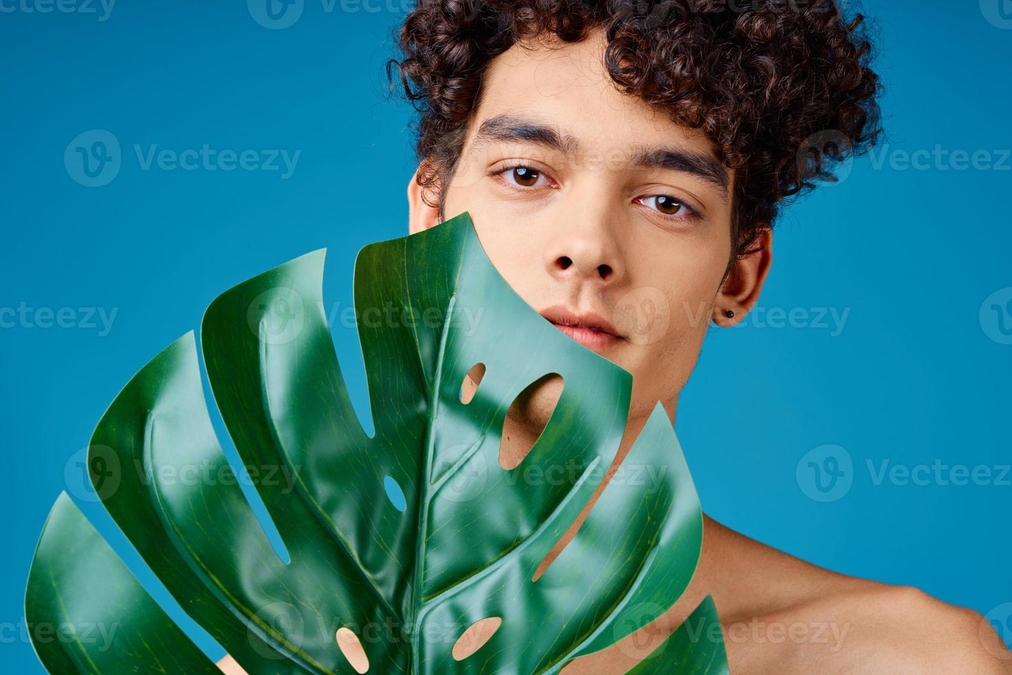 uomo con Riccio capelli nudo le spalle verde le foglie ecologia foto