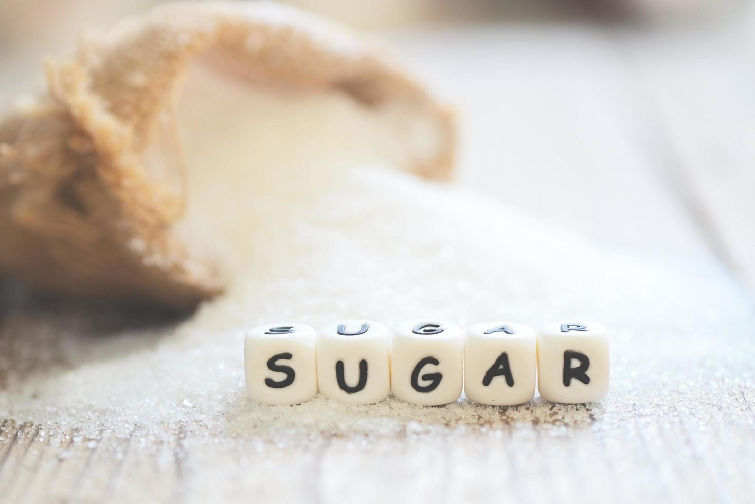 zucchero su sacco e di legno sfondo, bianca zucchero per cibo e dolci dolce caramella mucchio di dolce zucchero cristallino granulato foto