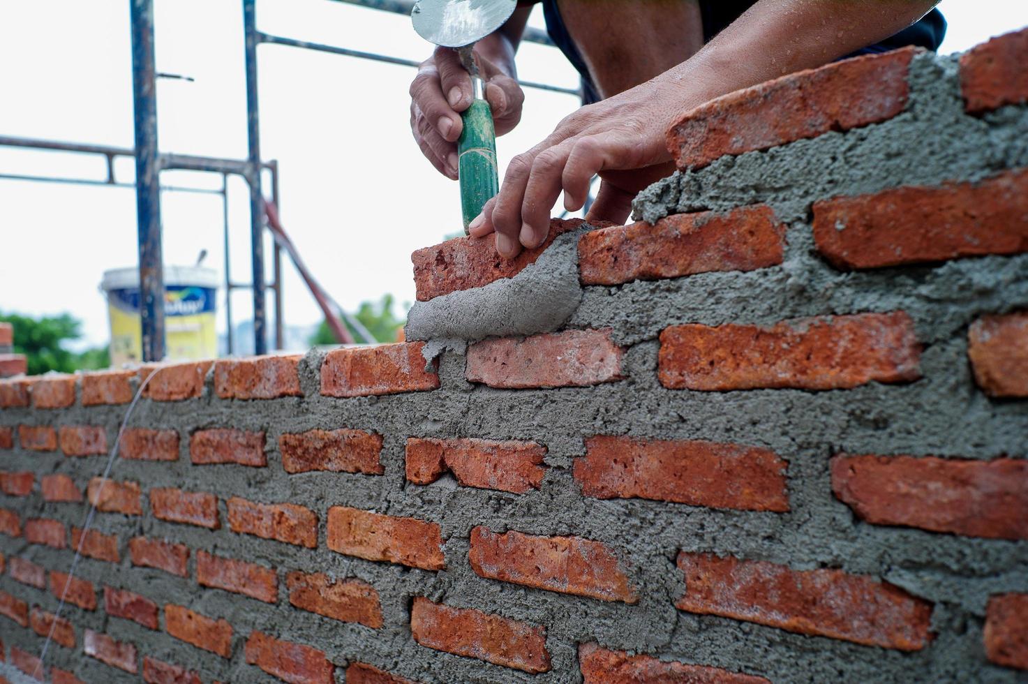 primo piano le mani del lavoratore che installa i muratori per la costruzione del muro in cantiere. foto