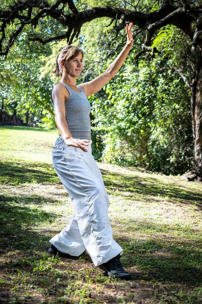 bellissimo e allegro adulto donna praticante tai chi nel parco. foto