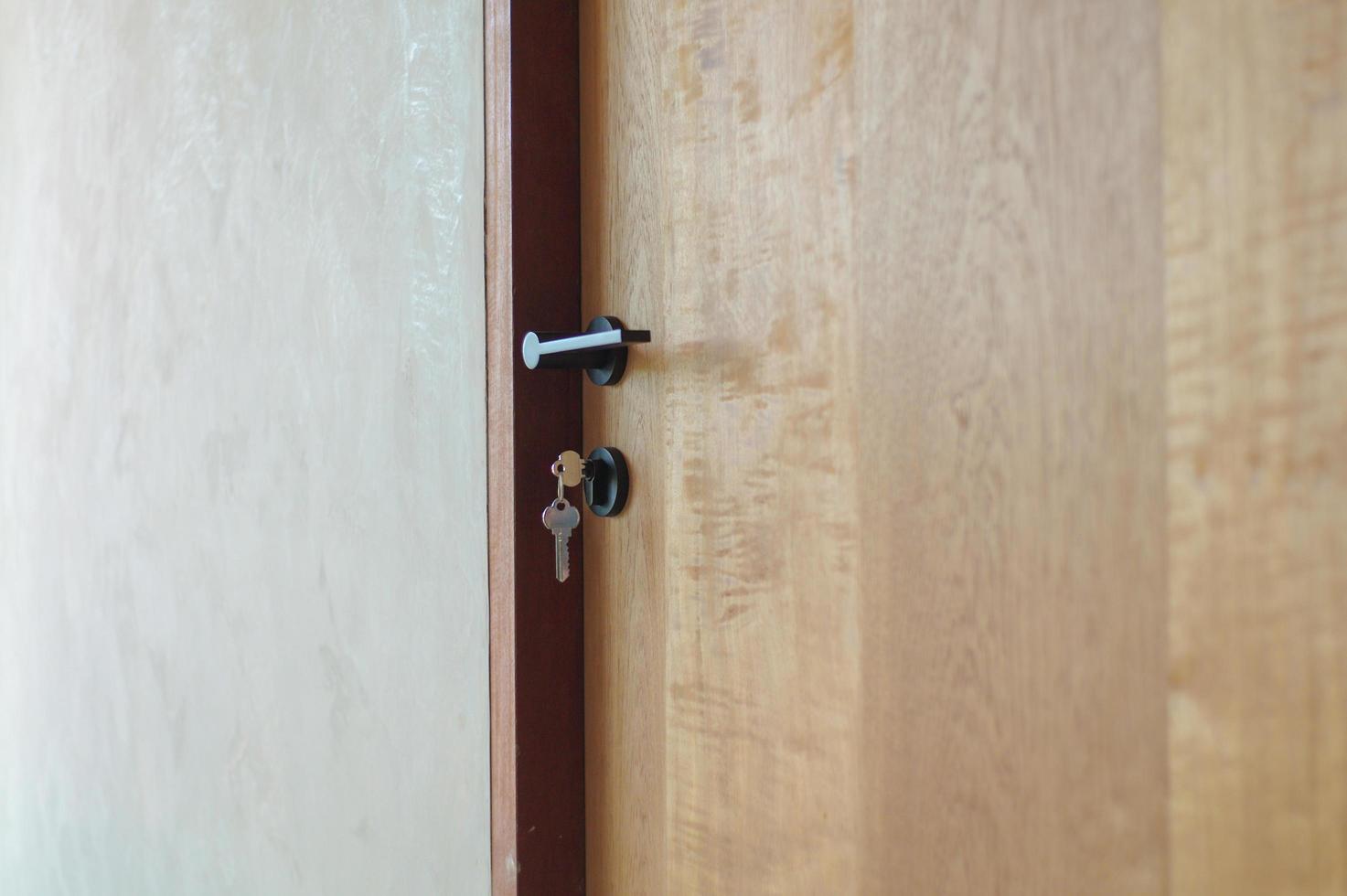 messa a fuoco selettiva sullo stile moderno della manopola sulla porta di legno con chiavi appese alla serratura foto