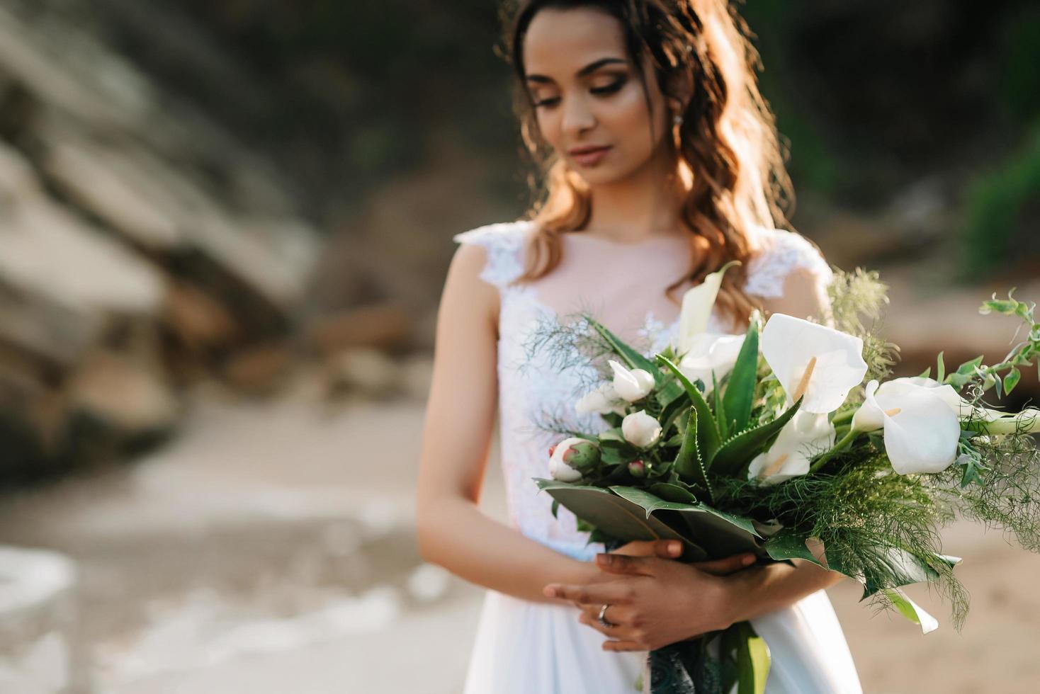 sposa con un bouquet da sposa sulla riva foto