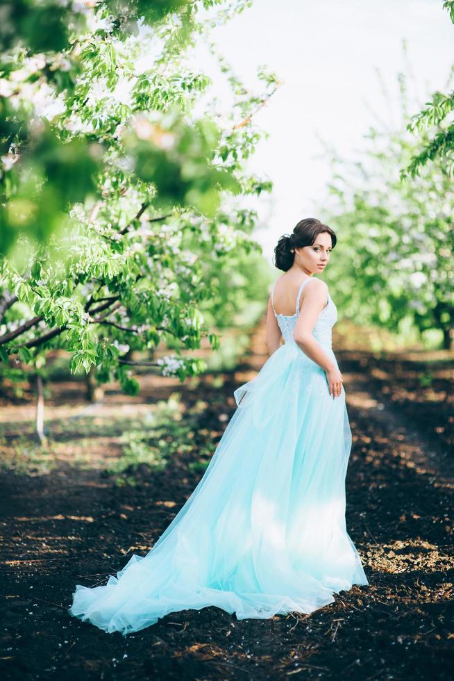 ragazza bruna in un abito turchese nel giardino primaverile foto