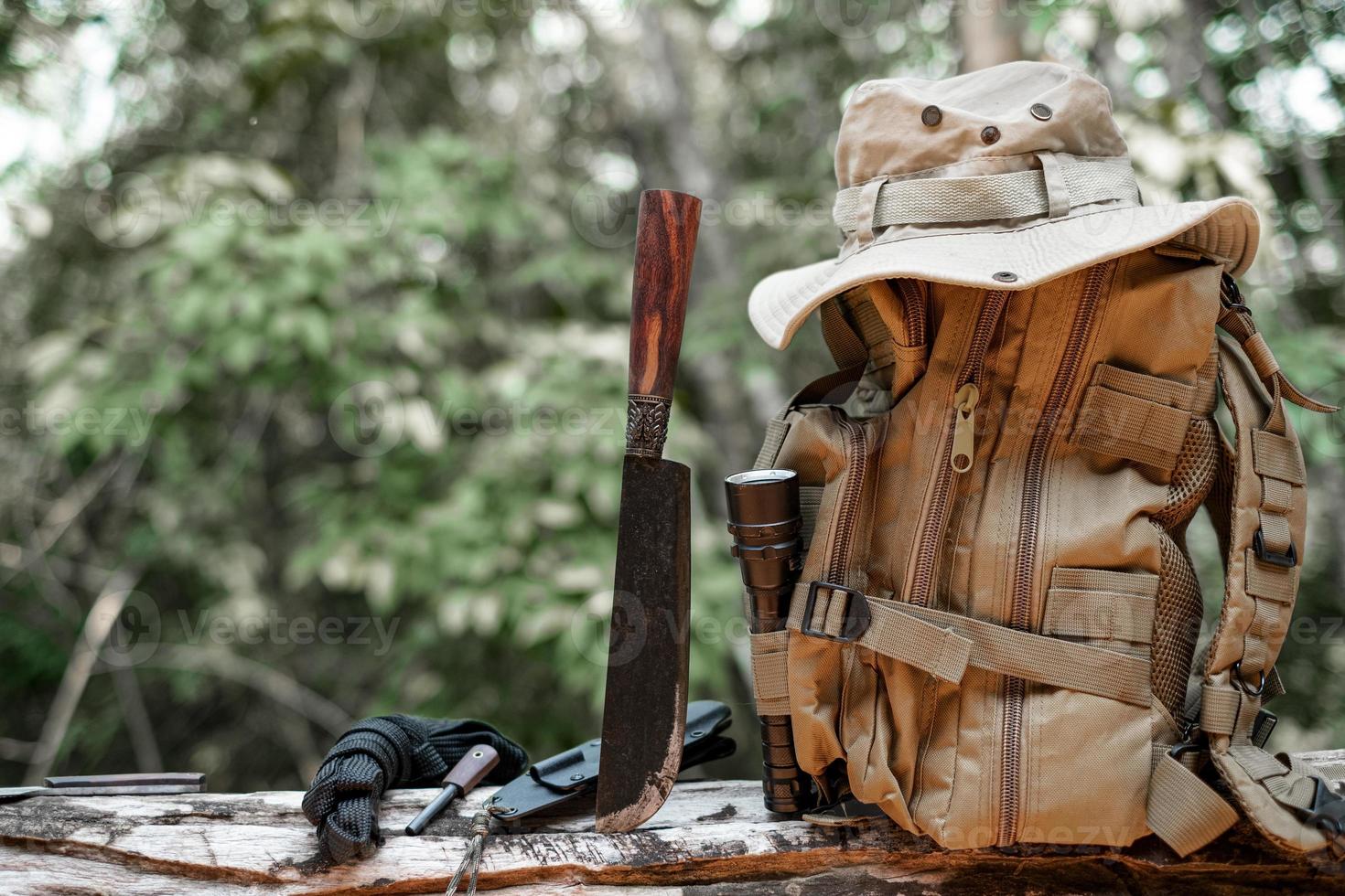 attrezzatura per sopravvivenza secchio cappello zaino escursioni a piedi coltello campeggio torcia elettrica riposo su di legno legname nel il sfondo è un' foresta foto