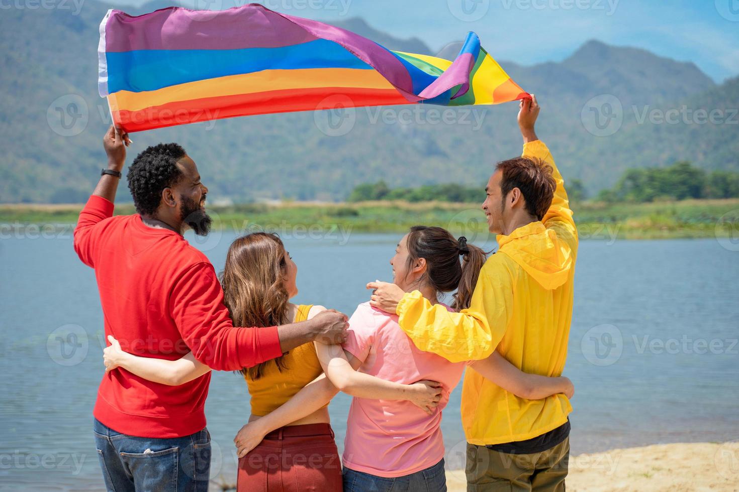 indietro Visualizza. giovane diversità persone avendo divertimento Tenere lgbt arcobaleno bandiera su il spiaggia. sostenitori di il lgbt Comunità foto